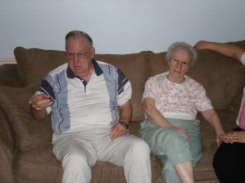 2000 Ford Crown Victoria - An older couple sits on a couch, with a third person's arm visible on the right side of the frame.