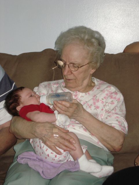 2000 Ford Crown Victoria - A grandmother lovingly feeds her grandchild from a bottle while sitting on a couch.