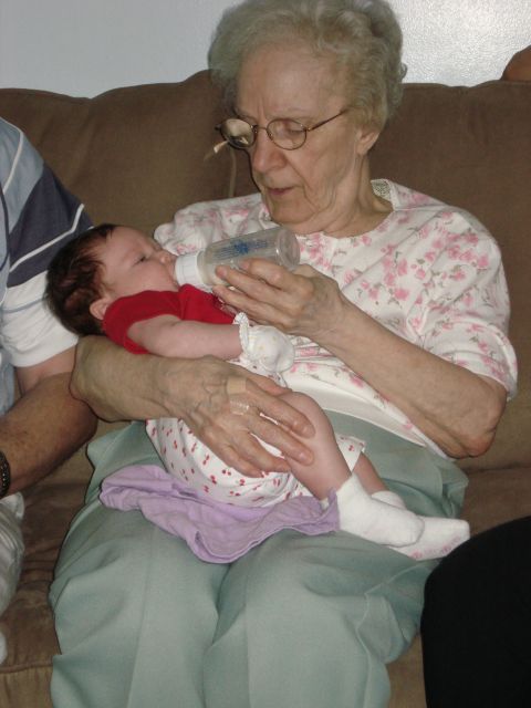 2000 Ford Crown Victoria - An elderly woman feeds a baby from a bottle while sitting on a couch.