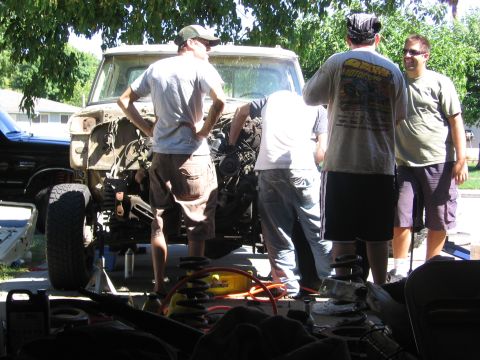 1989 Ford Bronco - A group of men work on the front end of a disassembled Ford truck, with another vehicle visible to the side.