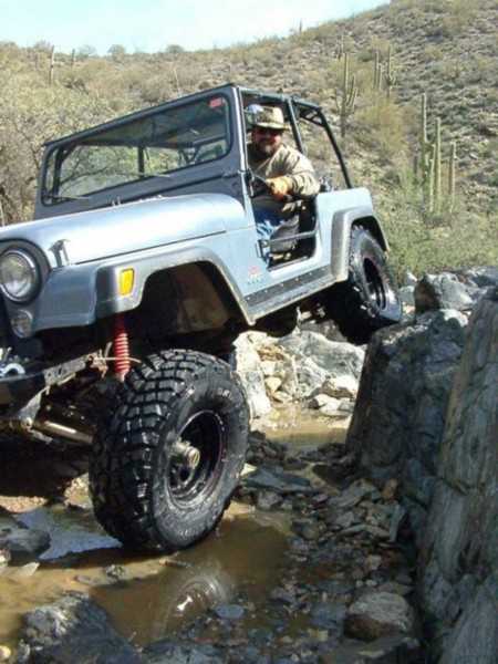 1983 Jeep CJ7 - Driver maneuvers a 1983 Jeep CJ7 through a rocky, wet off-road course.