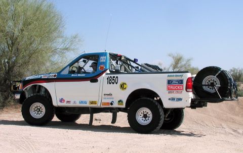 2000 Ford F-150 - A modified 2000 Ford F-150 truck with racing decals and a spare tire is seen from the side in an outdoor setting.