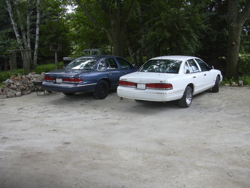 1997 Ford Crown Victoria and a blue Ford Crown Victoria parked on gravel