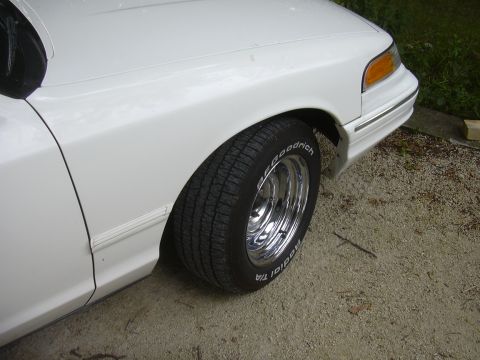 1997 Ford Crown Victoria - A white 1997 Ford Crown Victoria is shown from the front quarter angle, highlighting its chrome wheels and BFGoodrich tires.