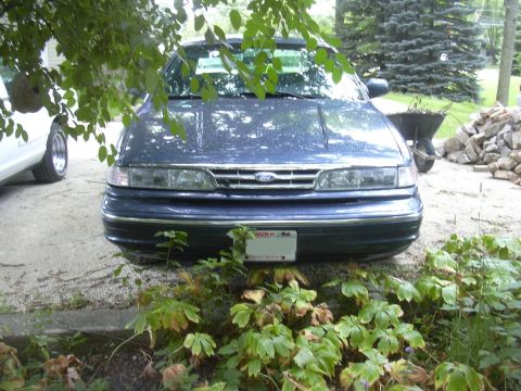 1997 Ford Crown Victoria - Front view of a blue 1997 Ford Crown Victoria, parked outdoors with plants obscuring the lower portion.