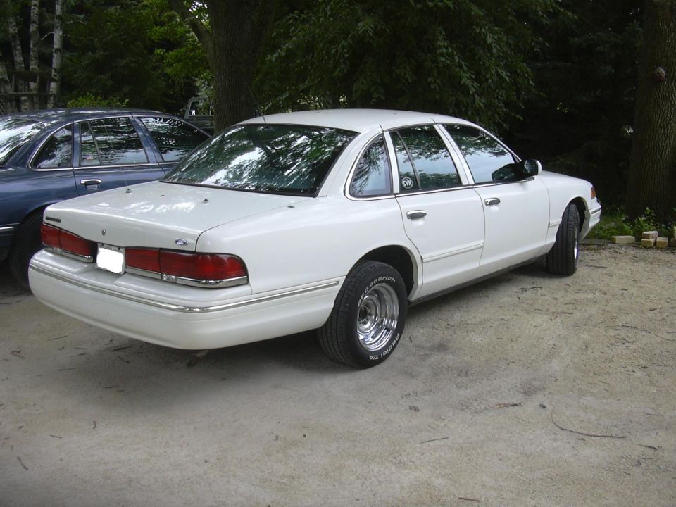 1997 Ford Crown Victoria, rear 3/4 view, parked on concrete next to a blue sedan