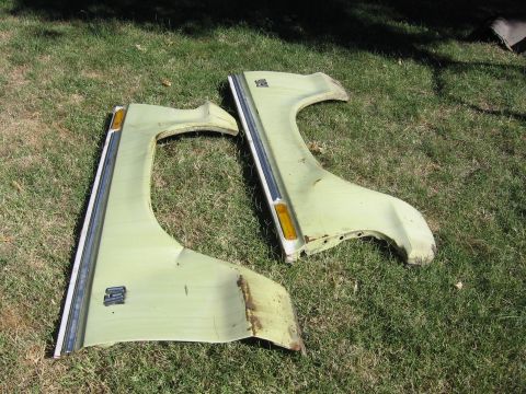 1989 Ford Bronco - Two old car fenders lie on the grass, showing signs of rust and wear.