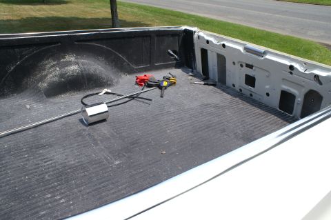 1972 Ford Ranchero - The interior of a truck bed is shown from a rear angle, with tools and a metal rod present.