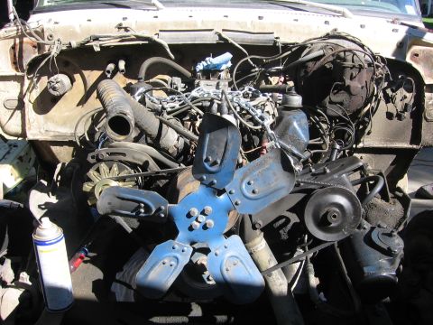 1989 Ford Bronco - The engine bay of a vehicle, a blue fan and a spray can on the side.
