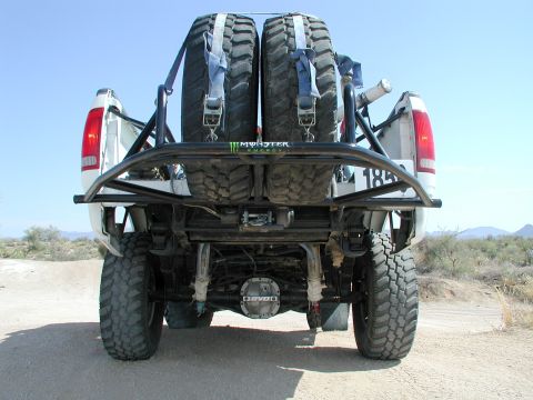 2000 Ford F-150 - Rear view of a modified 2000 Ford F-150 with a custom roll cage and spare tires mounted.