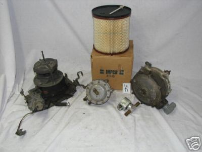 1978 Ford Bronco - A collection of propane fuel system components, including a carburetor, air filter, and regulator, are laid out on a white cloth.