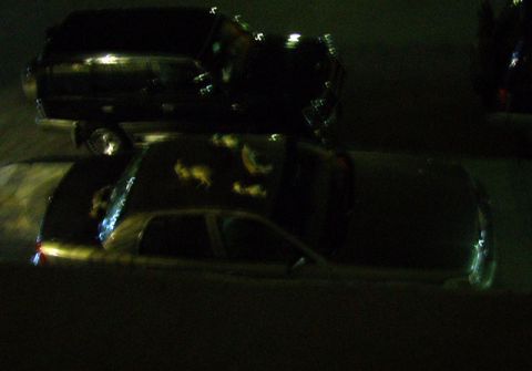 2007 Mercury Grand Marquis - Two vehicles are parked together at night, with one car precariously balanced on top of another.