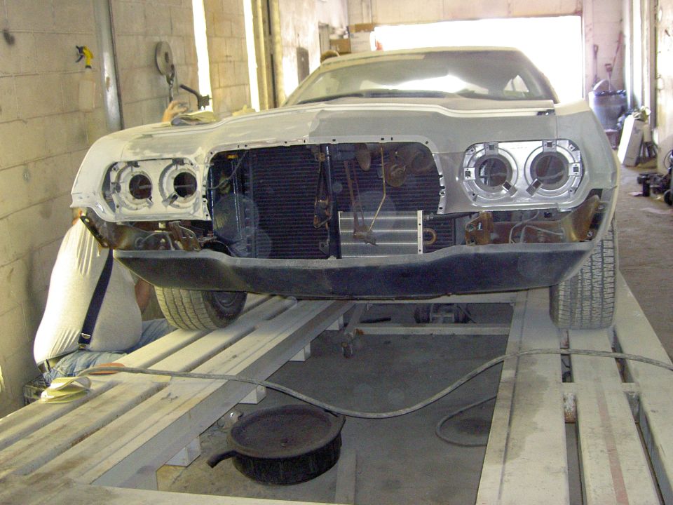 Ford Ranchero front end stripped to primer on a shop lift with grille and headlights removed