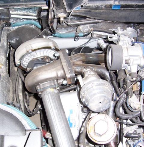 1988 Pontiac Fiero - Engine bay detail showing a turbocharger and associated exhaust and intake piping.