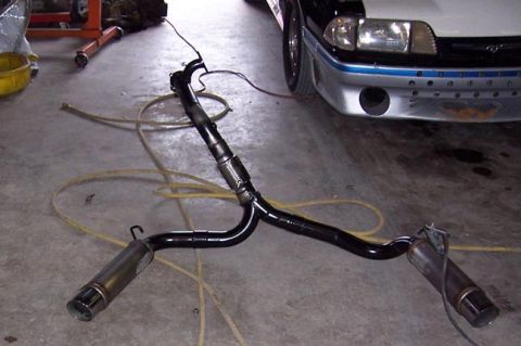 1988 Pontiac Fiero - An exhaust system lies on the floor, with a portion of a car visible in the background.