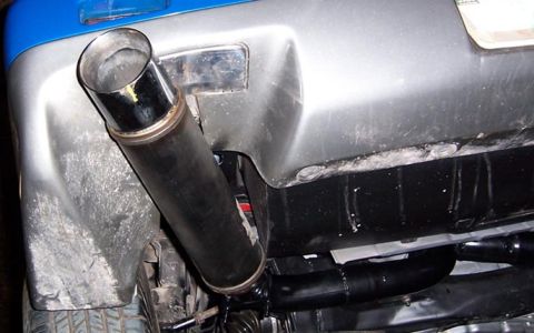 1988 Pontiac Fiero - A close-up view of a car's exhaust pipe, showing aftermarket modifications.