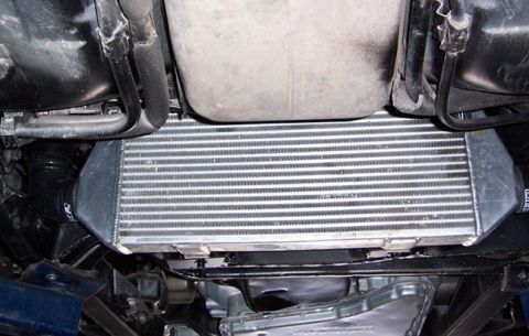 1988 Pontiac Fiero - Close-up of a vehicle's intercooler assembly, showing the finned radiator and connecting hoses.