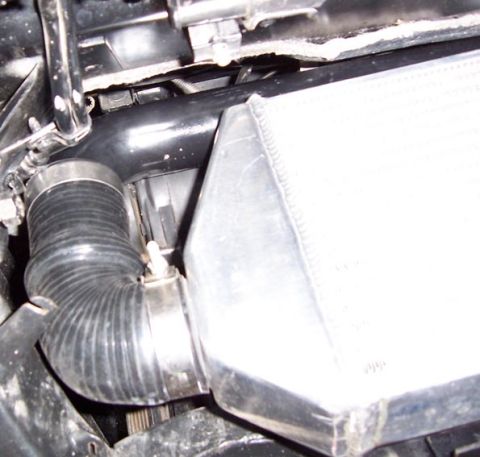 1988 Pontiac Fiero - Close-up view of an intercooler and a flexible hose connection in a vehicle's engine bay.