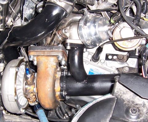 1988 Pontiac Fiero - Close-up view of engine components, including a turbocharger and associated plumbing.