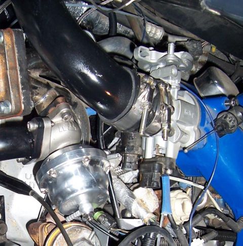 1988 Pontiac Fiero - Close-up view of engine components including a turbocharger and wastegate.