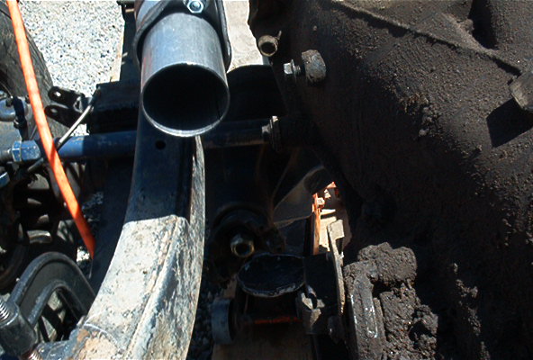 Close-up of an exhaust pipe and some suspension parts, possibly from a truck or SUV