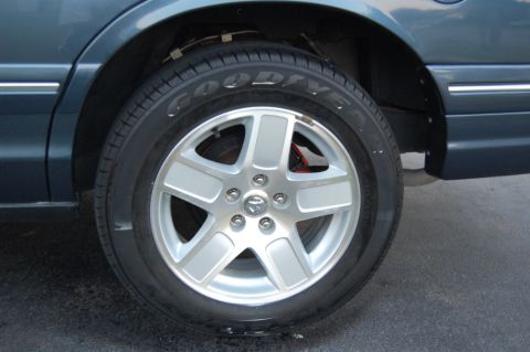 1985 Mercury Grand Marquis - Close-up view of a car's wheel and fender area, showing a silver rim and tire.