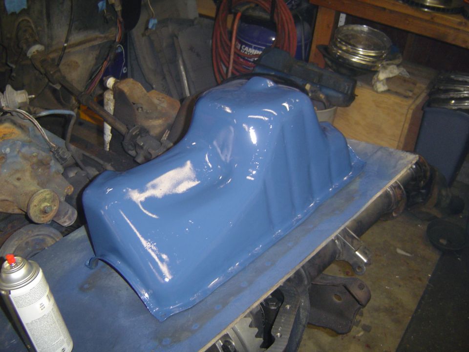 Freshly blue-painted engine oil pan resting on a bench in a shop