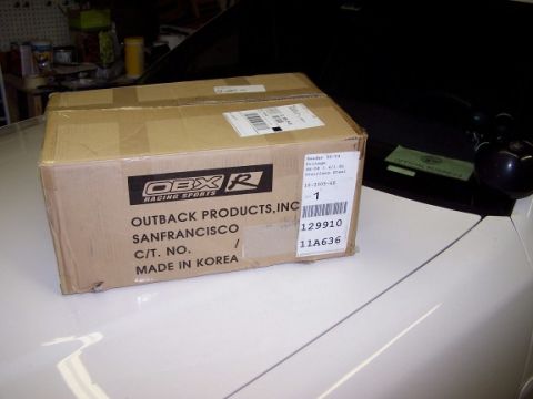 2000 Ford Crown Victoria - A cardboard box from Outback Products, Inc. is placed on the hood of a white vehicle.
