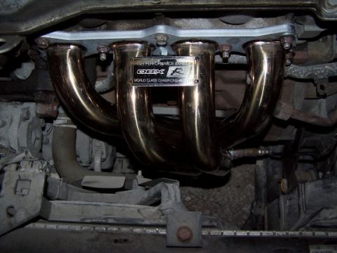 2000 Ford Crown Victoria - Close-up of an aftermarket exhaust manifold with visible branding and text.