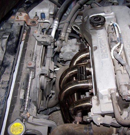 2000 Ford Crown Victoria - Close-up of a Mazda engine, showing the exhaust manifold and radiator fan.