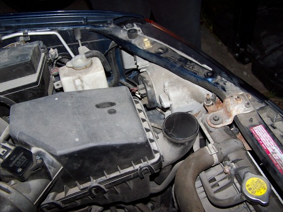 Close-up of a car's engine bay showing the air filter box, hoses, and radiator
