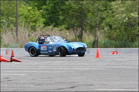 2001 Mercury Grand Marquis - A blue AC Cobra replica navigates an autocross course, marked by orange cones and adorned with racing decals.