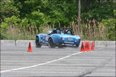 2001 Mercury Grand Marquis - A blue convertible sports car is seen from the rear, maneuvering through an autocross course with orange cones.