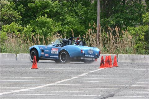 2001 Mercury Grand Marquis - A blue convertible sports car navigates an autocross course, kicking up dust as it turns.