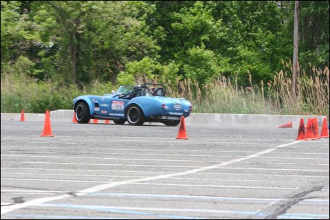 2001 Mercury Grand Marquis - A blue convertible sports car is seen from the rear on a race track, maneuvering around orange cones.