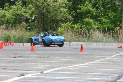 2001 Mercury Grand Marquis - A blue convertible sports car drives through an autocross course marked by orange cones.