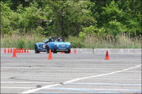 2001 Mercury Grand Marquis - A blue convertible sports car navigates an autocross course marked by orange cones.
