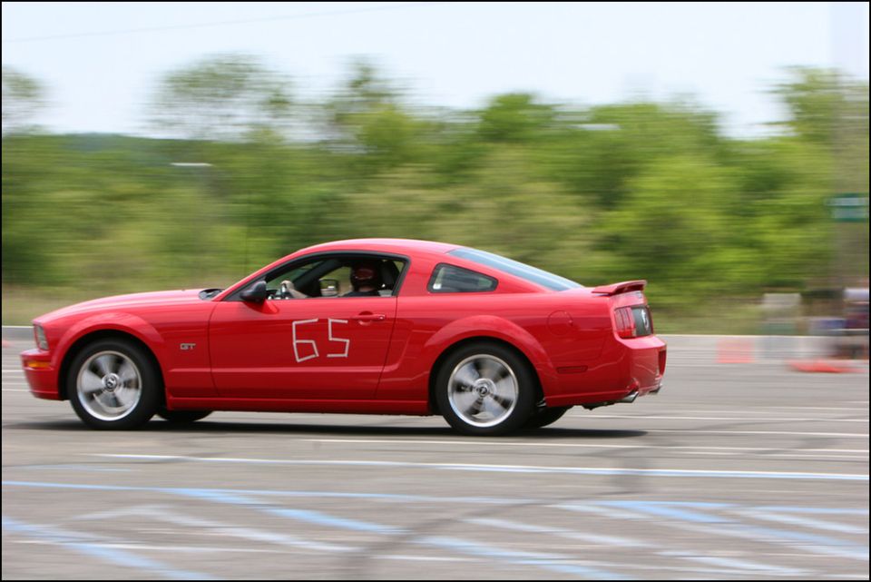 Red Ford Mustang GT with number 65 on the door, driving on a track