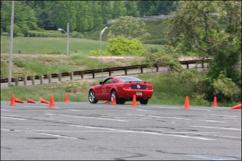 2001 Mercury Grand Marquis - Red Ford Mustang coupe navigates a course marked by orange cones on a sunny day.
