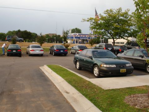 1993 Ford Taurus - Several cars are parked in a lot with a gas station in the background.