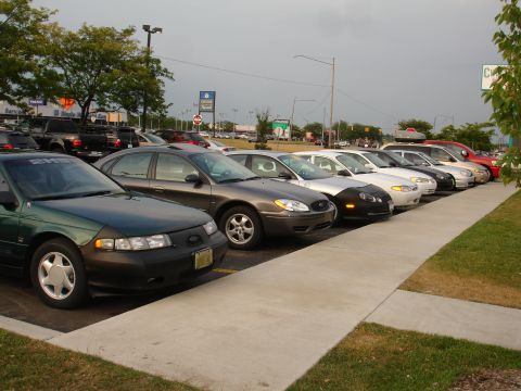 1993 Ford Taurus - A green 1993 Ford Taurus is parked in a lot with other vehicles.