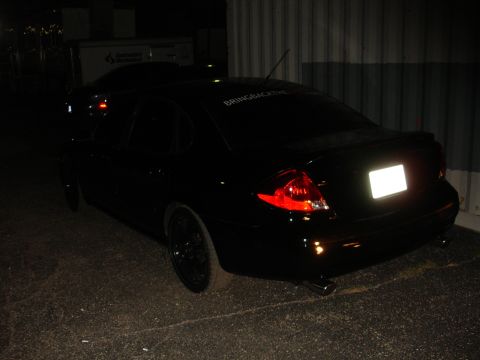 1993 Ford Taurus - Rear view of a black sedan with a custom decal on the rear window and a spoiler.