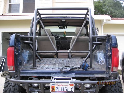 1994 Ford Bronco - This blue SUV features a prominent custom roll cage and a personalized license plate reading 'PLUGLY'.