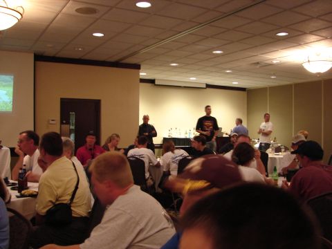 1993 Ford Taurus - A convention gathering with people seated at tables and speakers presenting at the front.