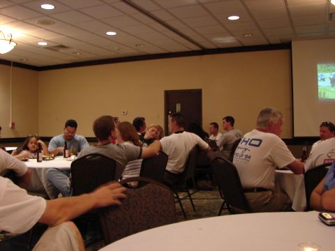 1993 Ford Taurus - Attendees are seated at tables in a conference room, with a projection screen displaying an image.