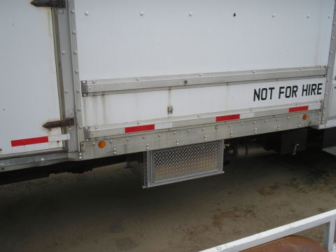 1999 Ford F-800 - Side view of a white truck box with reflective tape and a metal storage compartment below.