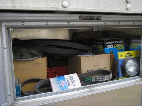 1999 Ford F-800 - Contents of a truck's storage compartment include belts, hydraulic jacks, and a headlight.