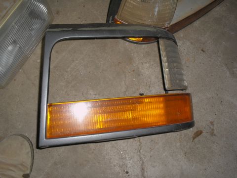 1990 Ford Bronco - Headlight assembly from a Ford Bronco, likely from the 1980s, is shown on a concrete floor.