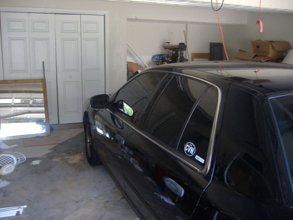 Black sedan with CVN window sticker parked inside a garage, driver's side view