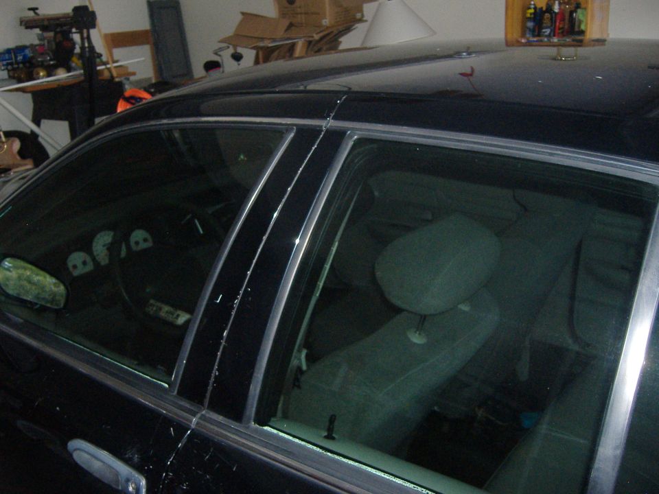 Black sedan in a garage, driver-side windows showing gray cloth interior and steering wheel